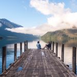 couple in love sitting on the pier at Nelson Lake National Park in the South Island of New Zealand