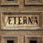 Paris, France - August 11, 2016: Background rusty plate and patina with Latin inscription "Eterna" (Eternity) engraved. Detail of the door of a chapel abandoned. Pere Lachaise Cemetery.
